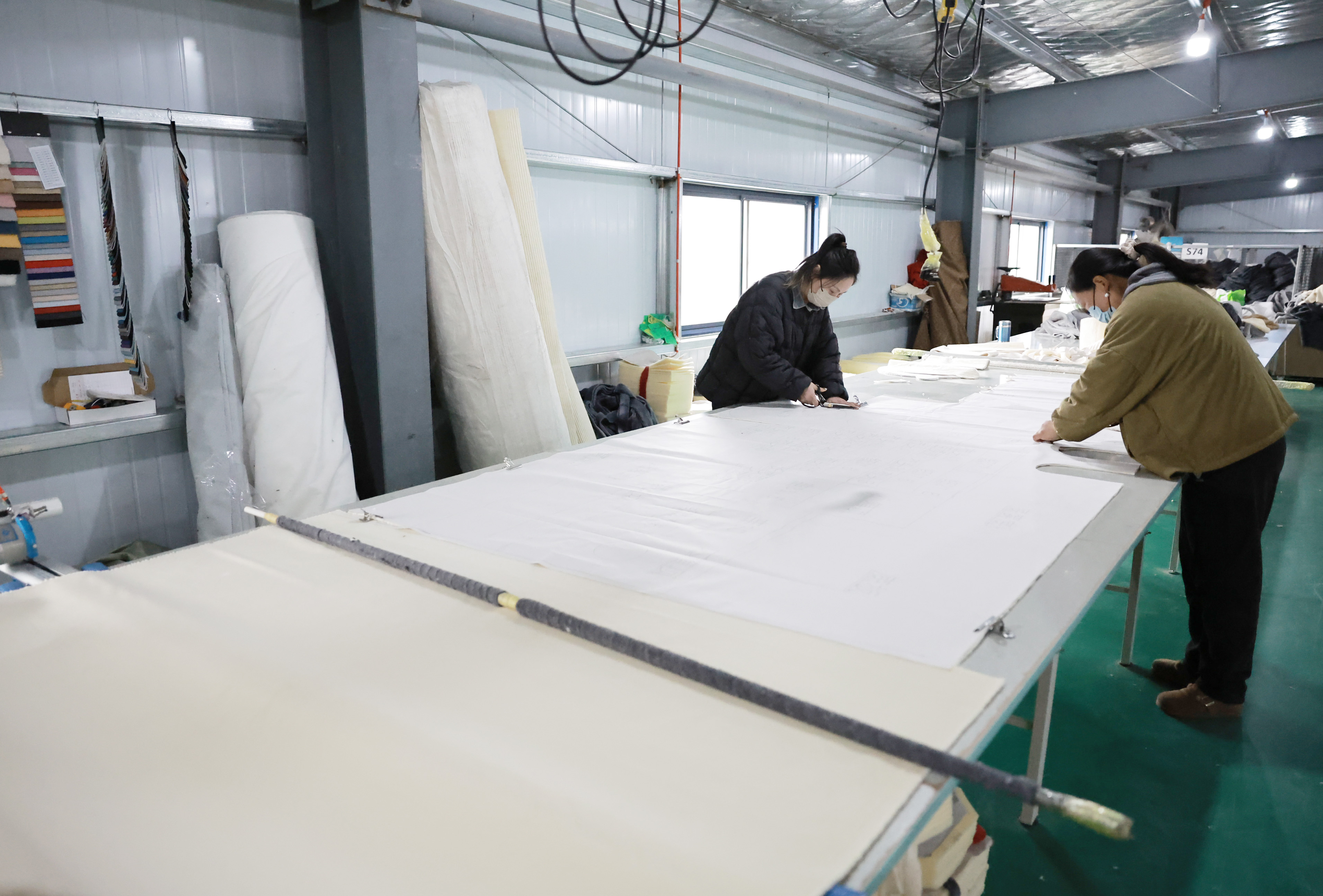 工人正在车间裁剪布料。 工人正在车间裁剪布料。